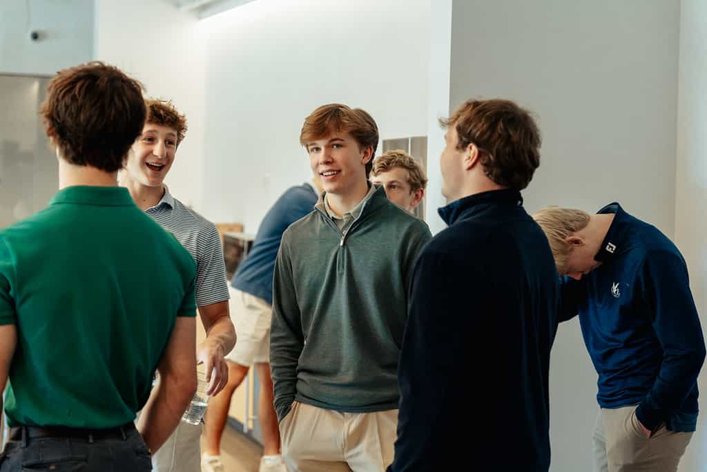 Group of high school boys talking and laughing together indoors at PCPC’s High School Ministry in Dallas.