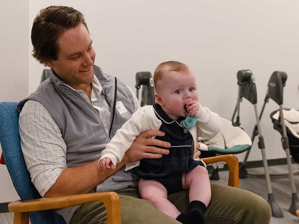Volunteer holding baby during church gathering.