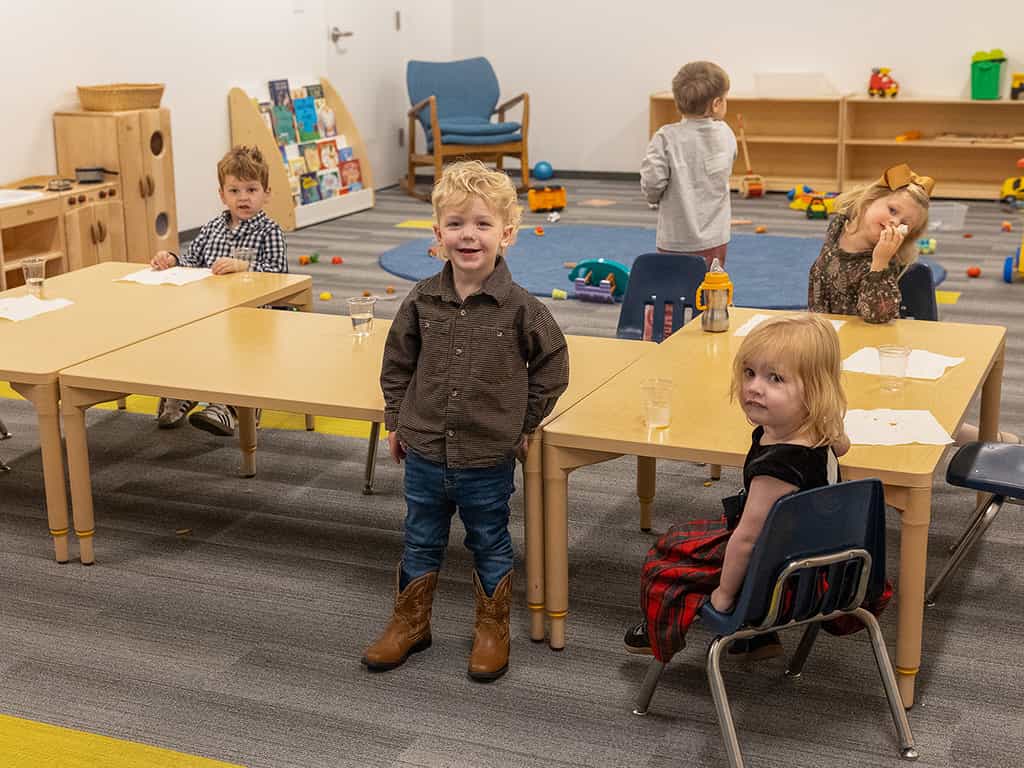 Toddlers playing and snacking in church nursery classroom.