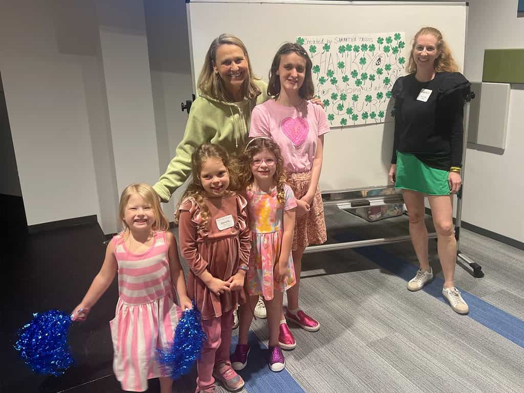 Volunteers and children smiling in front of a thank-you poster at a Dallas church with a special needs program.