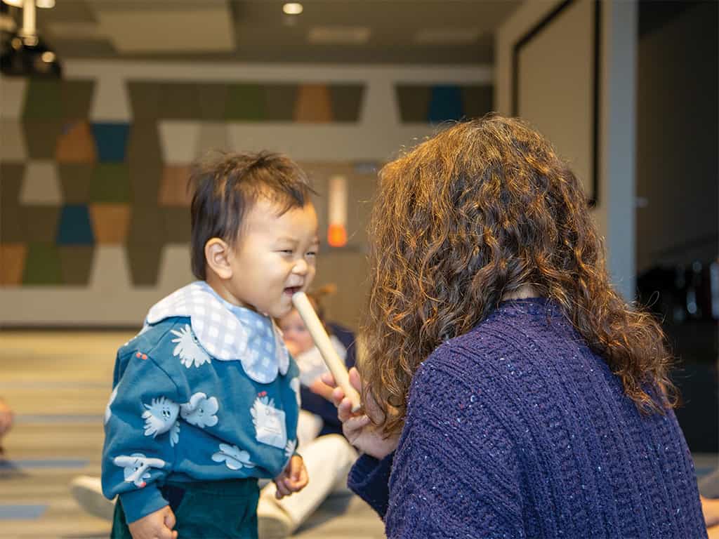 Toddler smiling and interacting with a teacher during toddler music classes in Dallas, TX.