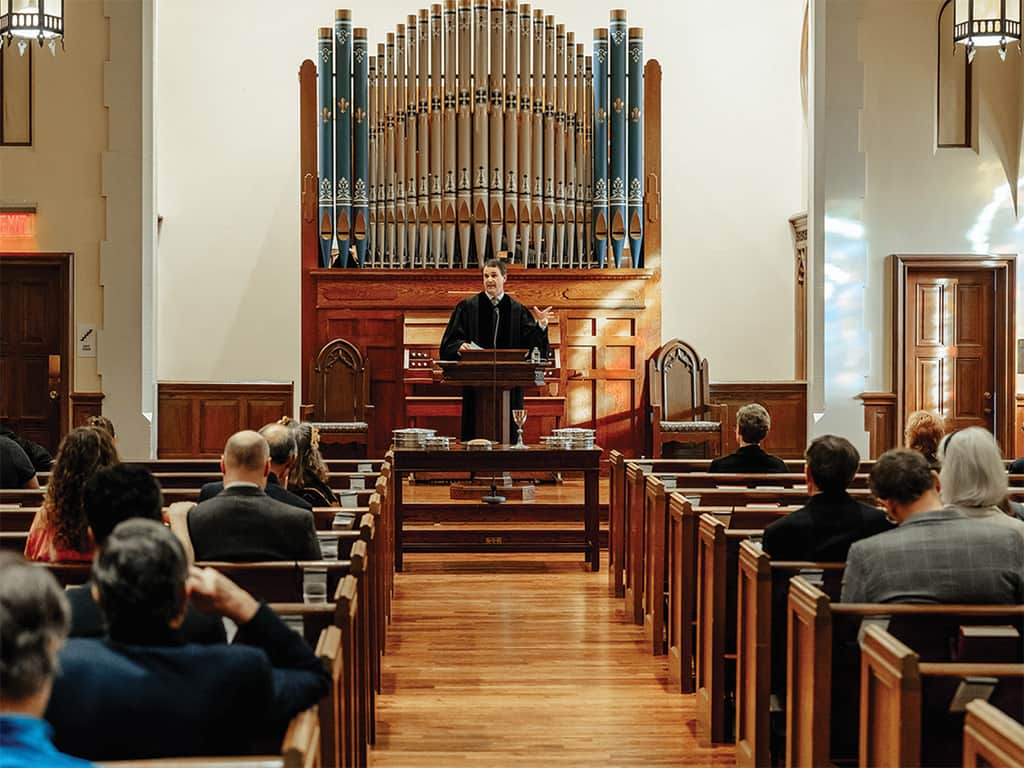 Pastor preaching from the pulpit during a Presbyterian church service as the congregation listens in wooden pews.