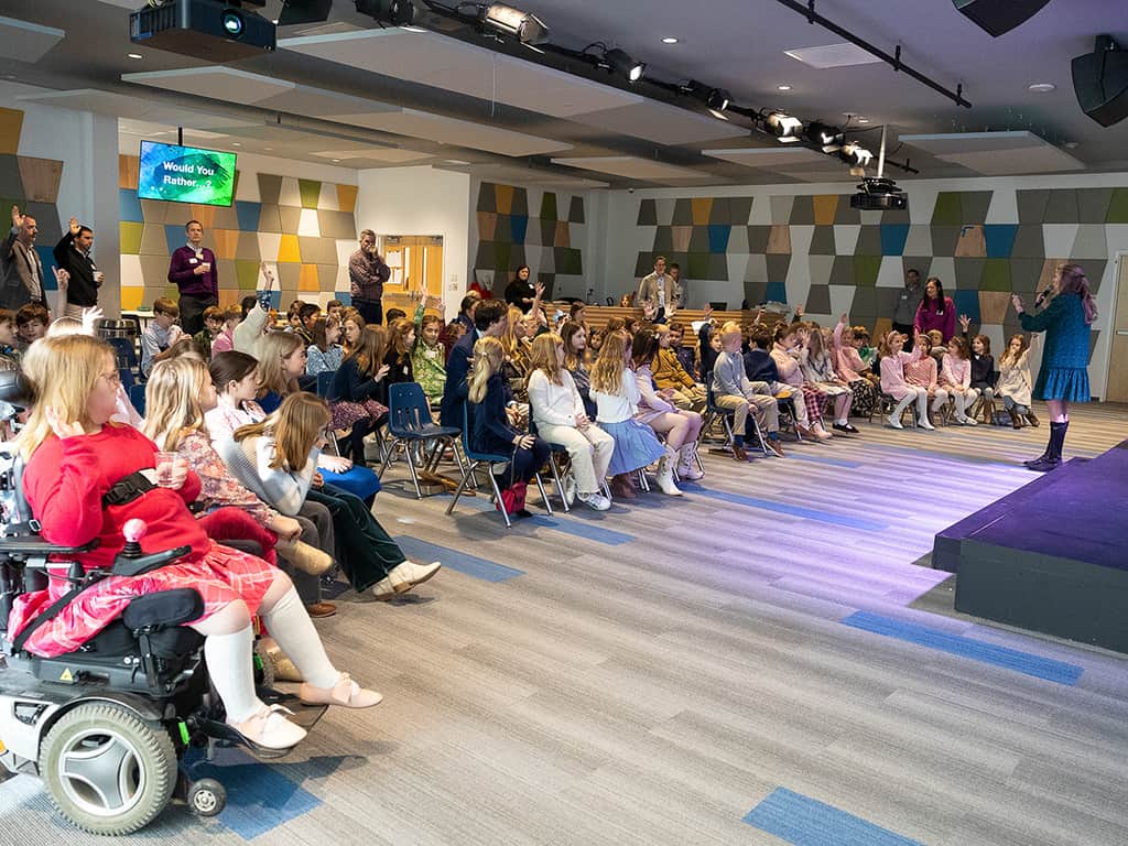 A large group of children seated in a modern church classroom during a kids ministry gathering.