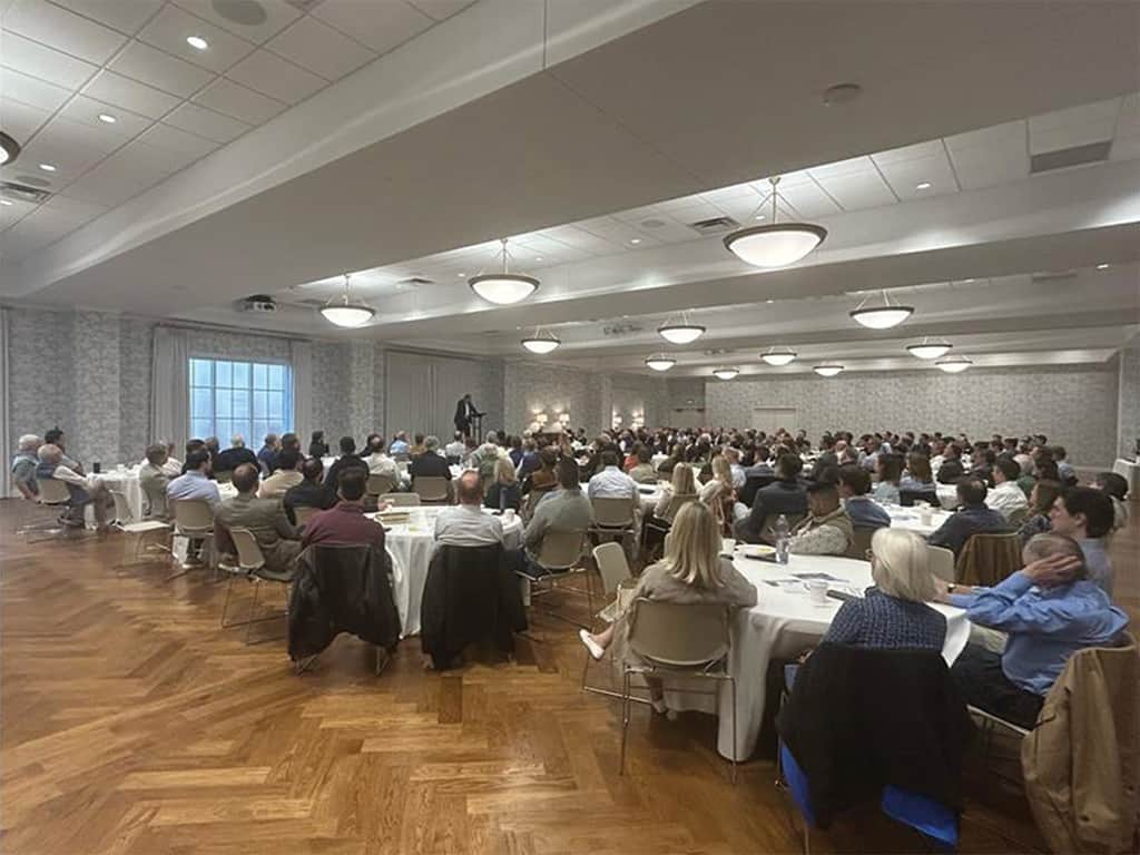Large church gathering seated at round tables listening to speaker.