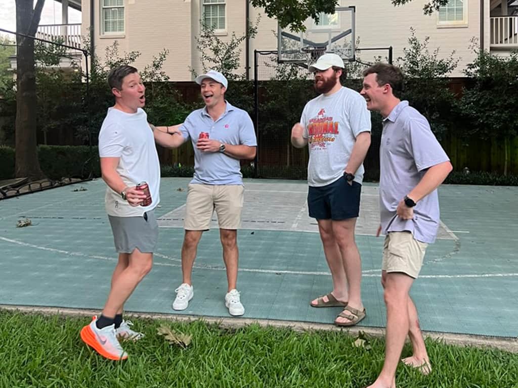 Four men at PCPC's Young Adult Ministry laughing and talking together on an outdoor basketball court.