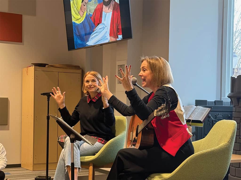 Women leading songs and storytelling with a guitar during a Preschool Ministry gathering.
