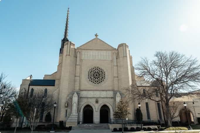 Front exterior view of the Park Cities Presbyterian Church sanctuary with large rose window and twin arched entrances.