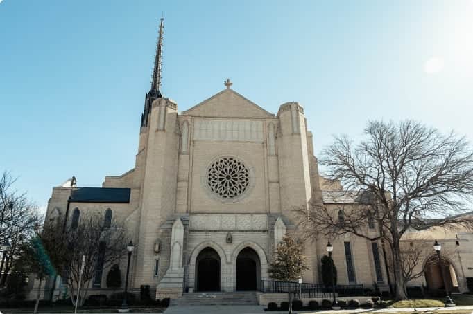 Front exterior view of the Park Cities Presbyterian Church sanctuary with large rose window and twin arched entrances.