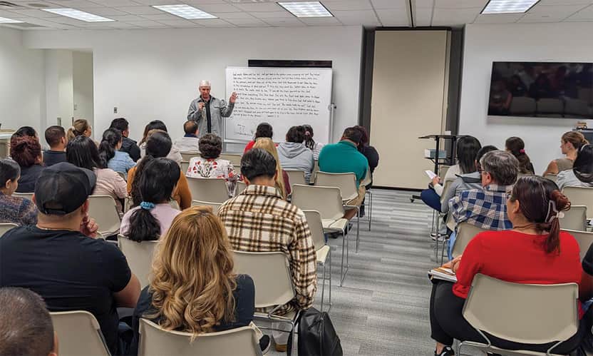 Adult Bible study class with teacher speaking at whiteboard.